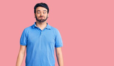 Günlük kıyafetler giyen genç İspanyol adam komik yüzlü yanakları şişiriyor. Havayla şişmiş ağız, çılgın bir ifade.. 