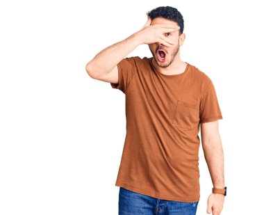 Gündelik kıyafetler giyen genç İspanyol adam şok içinde yüzünü ve gözlerini kapayarak utanmış ifadesiyle parmaklarından bakıyor.. 