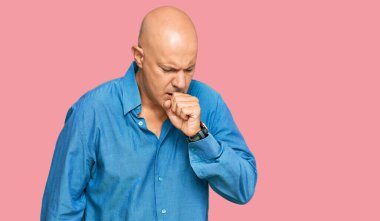 Orta yaşlı kel bir adam günlük kıyafetler giyip kendini kötü hissediyor ve soğuk algınlığı veya bronşitin belirtisi olarak öksürüyor. sağlık hizmeti kavramı. 