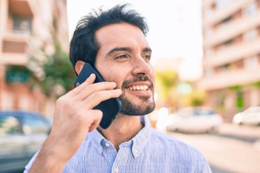 Genç İspanyol adam gülümsüyor. Şehirdeki akıllı telefondan konuşuyor..