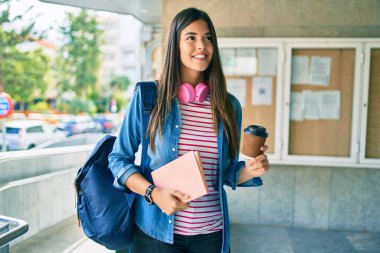 Genç İspanyol öğrenci gülümseyerek kitabı tutuyor ve üniversitede kahve içiyor..