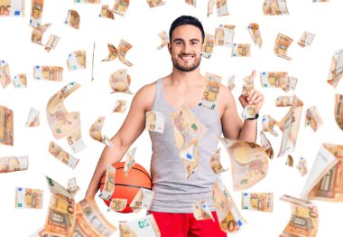 Basketbol topu tutan genç yakışıklı bir adam bir fikre ya da soru işaretine şaşırdı ve mutlu bir yüzle işaret etti.