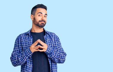 Latin asıllı genç adam rahat ve neşeli gülümseyerek ellerini birleştirip gülümsedi. Başarı ve iyimserlik 