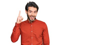 Gündelik kıyafetler giyen genç İspanyol adam başarılı bir fikirle işaret ediyor. Heyecanlı ve mutlu. Bir numara.. 