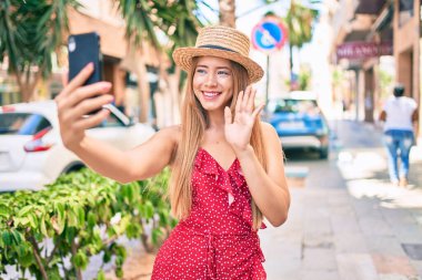 Kafkasyalı genç turist kız gülümseyerek şehirde akıllı telefon kullanarak video araması yapıyor..