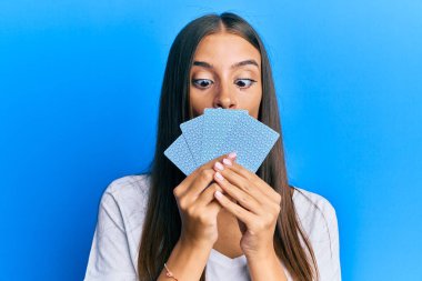 Poker oynayan genç İspanyol kadın kartlarla yüzünü kapatıyor balık suratlı, şaşı gözlü, çılgın ve komik bakışlı.. 