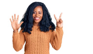 Güzel Afro-Amerikalı kadın günlük süveter giyer ve yedi numaralı parmaklarını göstererek gülümserken kendinden emin ve mutlu.. 