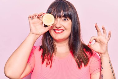 Limon tutan genç ve iri bir kadın parmaklarıyla imza atıyor, gülümseyerek mükemmel bir sembol oluşturuyor. 