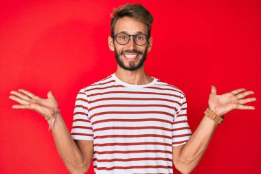 Sakallı, sıradan giyinmiş ve gözlüklü yakışıklı beyaz adam zaferi mutlu bir gülümsemeyle kutluyor ve ellerini kaldırarak kazanan yüz ifadesi sergiliyor. 