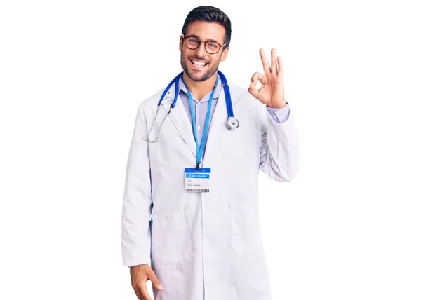 Doktor Üniforması Steteskop Giymiş Genç Spanyol Adam Gülümsüyor Parmaklarıyla Tamam — Stok fotoğraf