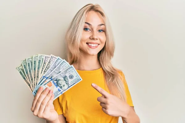 Vacker Kaukasiska Blond Flicka Håller Dollar Ler Glad Pekar Med — Stockfoto