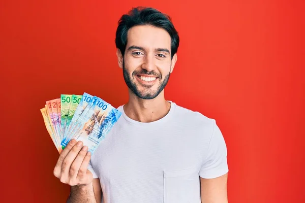 Ung Latinamerikansk Man Håller Schweiziska Franc Sedlar Ser Positiv Och — Stockfoto