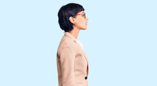 Young brunette woman with short hair wearing business jacket and glasses looking to side, relax profile pose with natural face with confident smile.