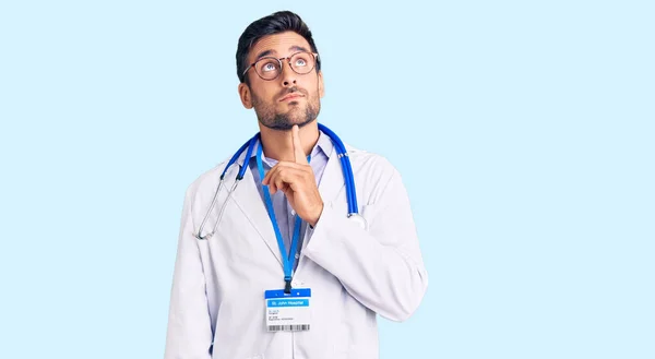 Joven Hombre Hispano Vistiendo Uniforme Médico Estetoscopio Pensando Concentrado Duda —  Fotos de Stock