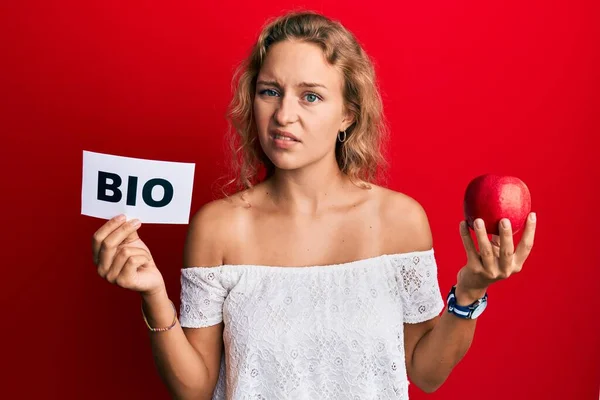 Krásná Běloška Držící Červené Jablko Bio Slovo Bezradný Zmatený Výraz — Stock fotografie