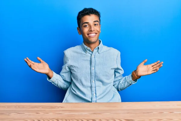 아프리카계 미국인 청년이 테이블에 양손을 벌리고 손바닥을 비교하고 광고하며 균형을 — 스톡 사진