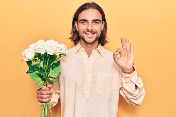 Νεαρός Όμορφος Άνδρας Κρατώντας Λουλούδια Κάνει Υπογράψει Δάχτυλα Χαμογελώντας Φιλικό — Φωτογραφία Αρχείου