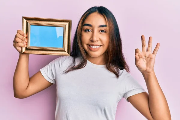 Jovem Mulher Latina Segurando Moldura Vazia Fazendo Sinal Com Dedos — Fotografia de Stock