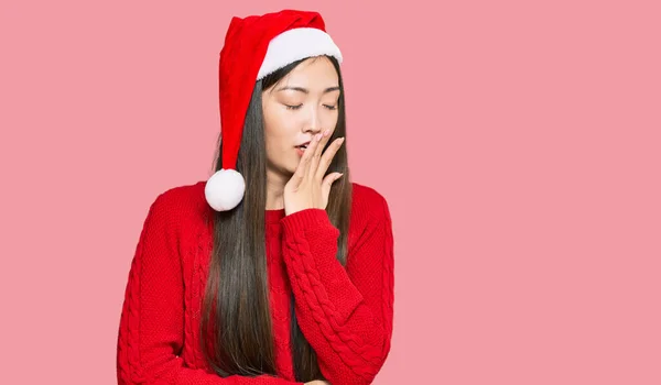 若い中国の女性は手で口をカバー疲れてあくび退屈クリスマスの帽子をかぶって 落ち着きもなく眠気もなく — ストック写真