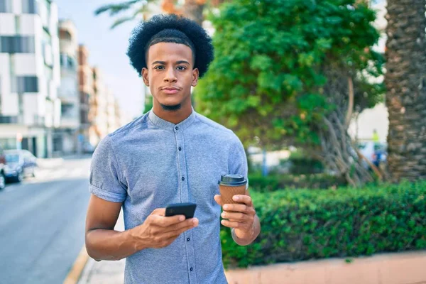 Young african american man with unhappy expression using smartphone and drinking coffee at the city.