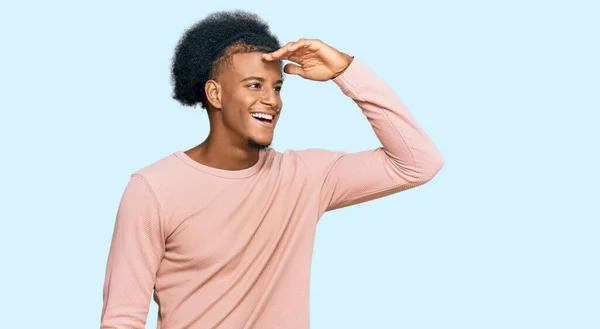 アフロの髪をしているアフリカ系アメリカ人の男性は カジュアルな服を非常に幸せと笑みを浮かべて遠くに手を頭で見ている 検索の概念 — ストック写真