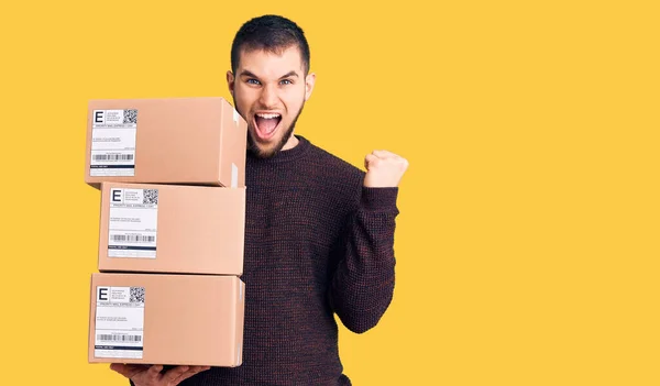 Jovem Homem Bonito Segurando Pacote Entrega Gritando Orgulhoso Celebrando Vitória — Fotografia de Stock