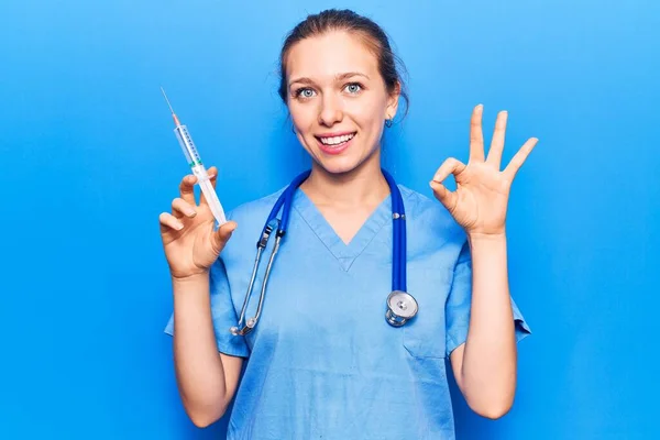 Şırınga Tutan Doktor Üniforması Giyen Genç Sarışın Kadın Parmaklarıyla Imza — Stok fotoğraf