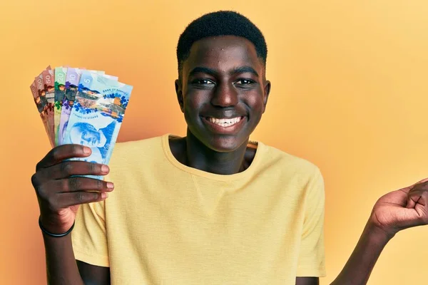 Νεαρός Αφροαμερικάνος Που Κρατάει Καναδικά Δολάρια Ουρλιάζοντας Περήφανος Γιορτάζοντας Νίκη — Φωτογραφία Αρχείου
