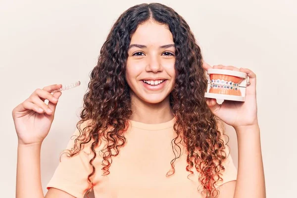 Adorable latin teenager smiling happy. Standing with smile on face holding denture with bracket and aligner over isolated white background — Stock Image Adorable Latin Teenager Smiling Happy Standing Smile Face Holding Denture Stock Photo