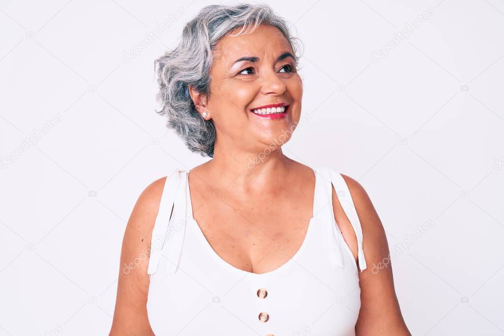 Senior hispanic woman wearing casual clothes looking away to side with smile on face, natural expression. laughing confident. 