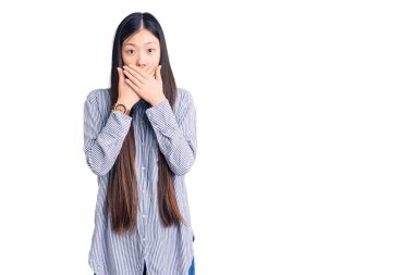 Gündelik tişört giyen genç, güzel Çinli kadın yanlışlıkla elleriyle ağzını kapatırken şok oldu. gizli kavram. 