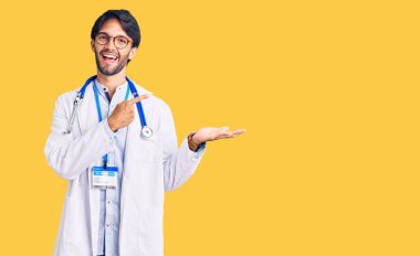 Doktor üniforması ve steteskop giyen yakışıklı İspanyol adam kameraya hayret ediyor ve gülümsüyor.. 