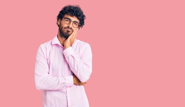 Kıvırcık saçlı ve ayı gibi giyinen yakışıklı genç adam kollarını kavuşturup depresyondan sıkılmış ve yorgun görünüyor.. 