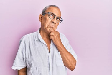 Yakışıklı, olgun, gündelik gömlek ve gözlük takan, şüpheye odaklanmış, çenesinde parmak olan ve kafasını kaldırıp, 