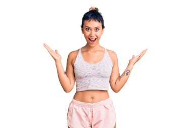 Spor giyinen genç bir kadın zaferi mutlu bir gülümsemeyle ve kazanan bir ifadeyle kutluyor. 