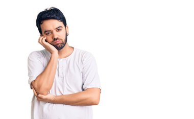 Günlük kıyafetler giyen genç İspanyol adam kollarını kavuşturarak depresyondan sıkılmış ve yorgun görünüyor.. 