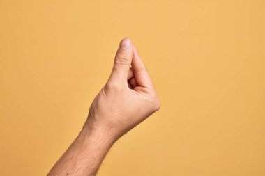 İzole edilmiş sarı arka planda parmaklarını gösteren beyaz bir adamın eli. Parmak, iş ve reklamla boş bir alan tutuyor.