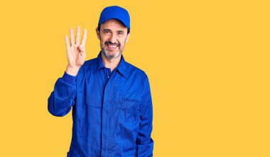 Orta yaşlı, tamirci üniforması giyen yakışıklı bir adam dört numarayı gösterip işaret ederken kendinden emin ve mutlu bir şekilde gülümsüyor.. 