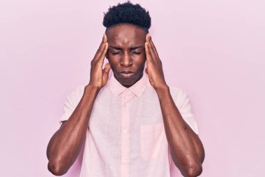 Genç Afro-Amerikan adam gündelik kıyafetler giyiyor. Baş ağrısı çekiyor, çaresiz ve stresli. Çünkü acı ve migren ağrısı var. Eller başının üstünde.. 