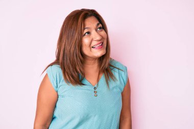 Orta yaşlı esmer, günlük kıyafetler giyen, yüzünde gülümsemeyle yan yana bakan İspanyol kadın, doğal bir ifade. Kendinden emin gülen. 