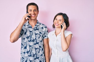 Akıllı telefondan konuşan güzel bir çift. Olumlu ve mutlu görünüyorlar. Dişlerini gösteren bir gülümsemeyle duruyorlar. 