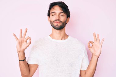 Yakışıklı, beyaz tişört giyen, rahat ve gülümseyen, gözleri kapalı meditasyon yapan, parmaklarıyla hareket eden İspanyol. yoga konsepti. 