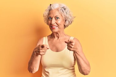 Gri saçlı, günlük kıyafetler giyen, mutlu ve komik yüzlü yaşlı bir kadın. iyi enerji ve titreşimler. 