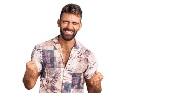 Yaz kıyafetleri giyen genç İspanyol adam başarı için heyecanlı kolları havada ve gözleri kapalı zaferi kutlarken gülümsüyor. Kazanan konsept. 