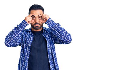 Günlük kıyafetler giyen genç İspanyol adam parmaklarıyla gözlerini açmaya çalışıyor, uykulu ve yorgun bir şekilde sabah yorgunluğu çekiyor. 