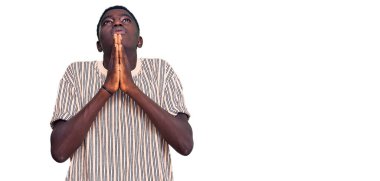 Genç Afro-Amerikalı bir adam günlük giysiler giyip elleri bağlı yalvarıyor ve dua ediyor. Yüzünde umut ifadesi var. Çok duygusal ve endişeli. Yalvarıyor. 