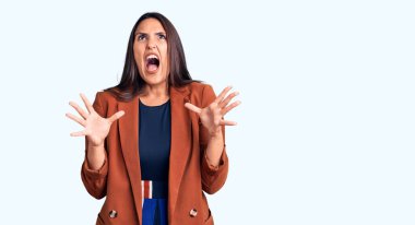 Zarif kıyafetler giyen genç, güzel esmer kadın deli gibi bağırıyor ve agresif bir ifadeyle bağırıyor ve kollarını kaldırıyor. hüsran kavramı. 