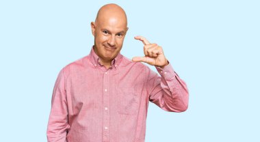 Orta yaşlı, kel, günlük kıyafetler giyen, gülümseyen, kendine güvenen, el hareketleriyle hareket eden, parmaklarıyla işaret yapan ve kameraya bakan bir adam. ölçüm kavramı. 