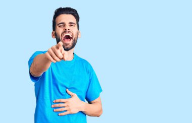 Sakallı, sıradan tişörtlü genç ve yakışıklı bir adam. Sana gülüyor, kamerayı işaret ediyor, vücudunu gösteriyor. Utanç ifadesi. 