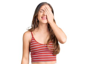 Güzel, beyaz bir kadın, günlük kıyafetler giyiyor. Bir gözünü eliyle kapatıyor. Yüzünde kendine güvenen bir gülümseme ve şaşırtıcı bir duygu var.. 